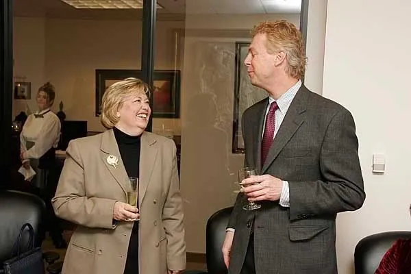 Two people standing next to each other holding wine glasses.