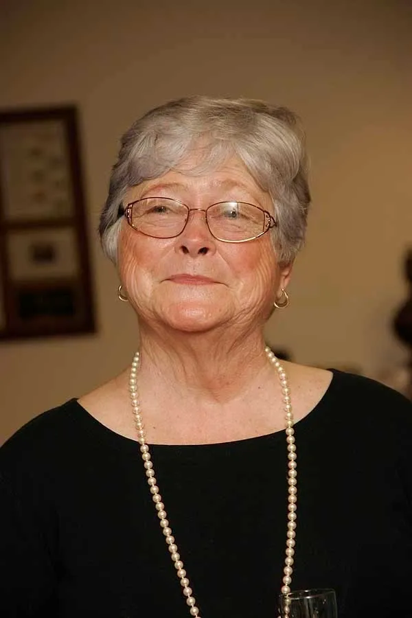 A woman with glasses and pearls in her hair.