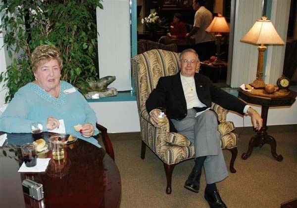 A man and woman sitting in chairs at a table.